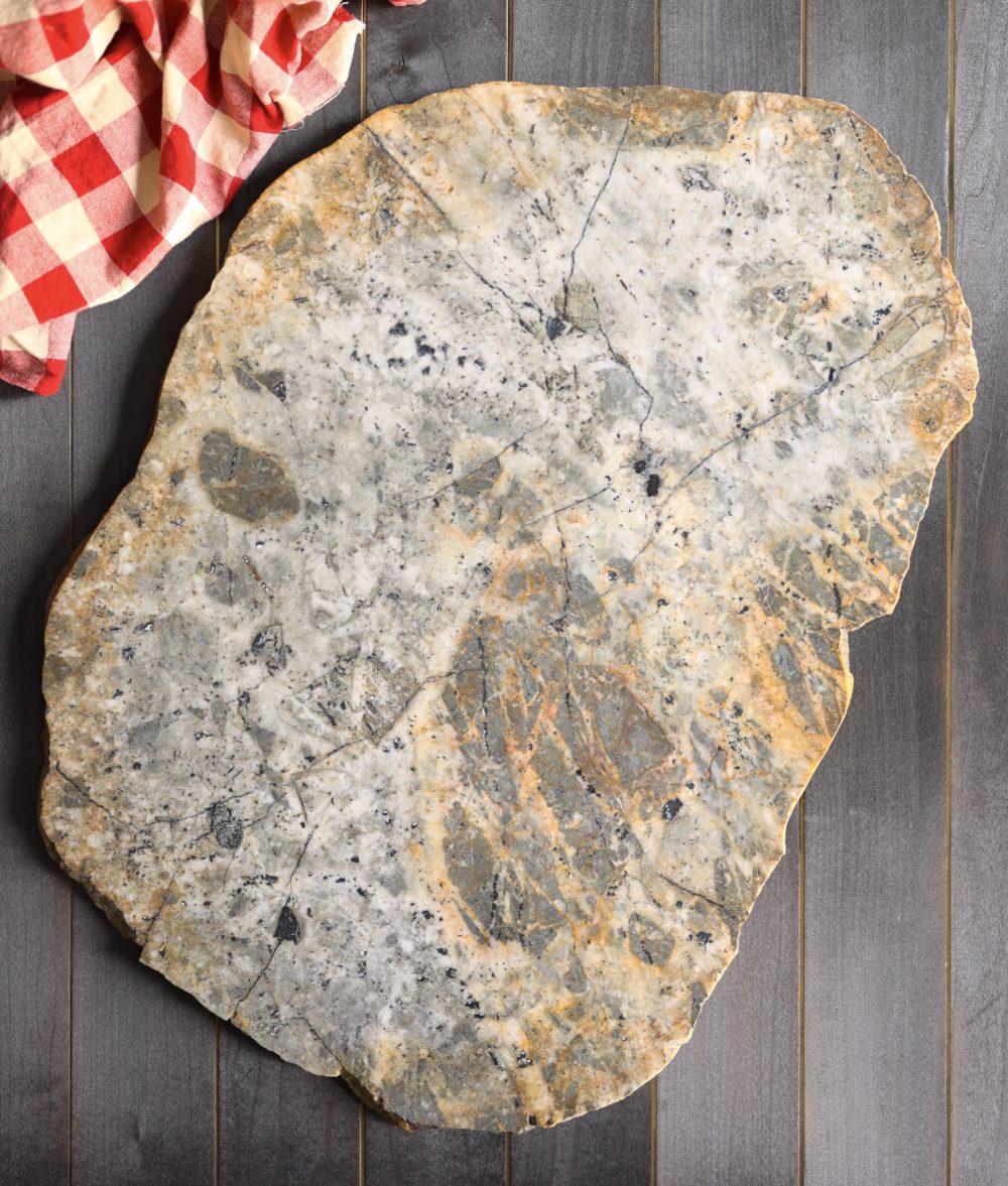 metamorphic stone charcuterie board with red, white and green colors with red and white napkin on top of a wooden background