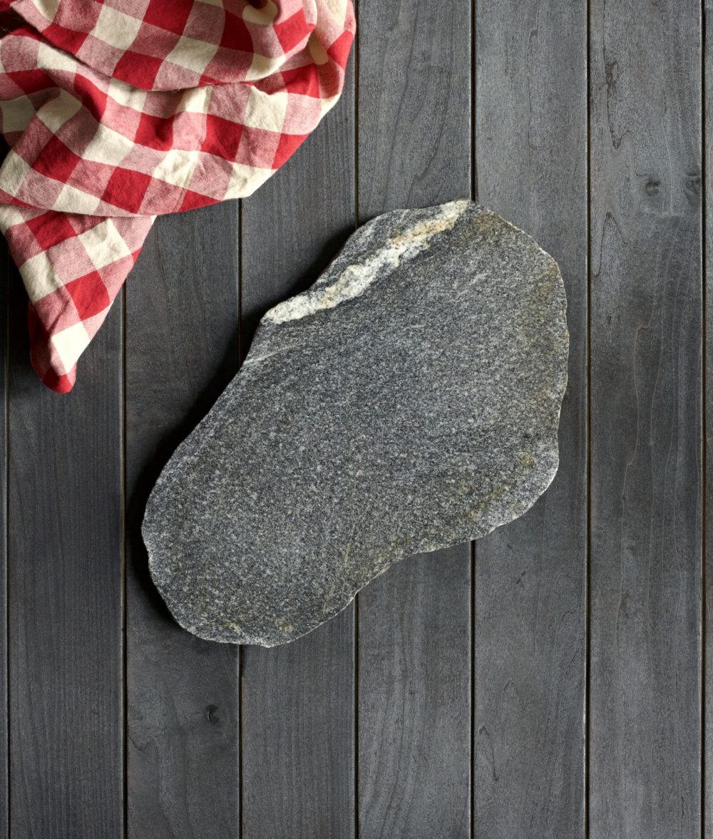metamorphic stone charcuterie board with gray, white and yellow colors with red and white napkin on top of a wooden background
