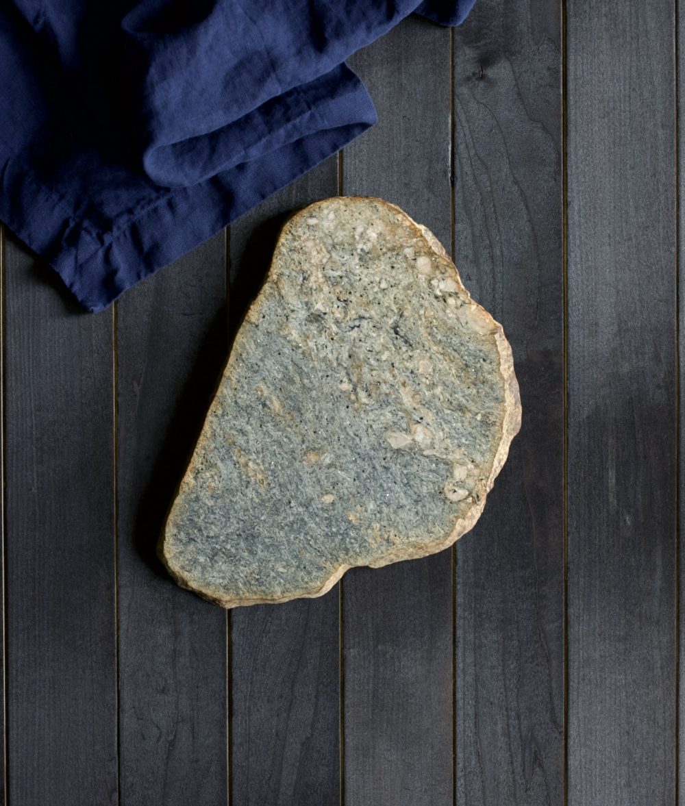 metamorphic stone charcuterie boards with gray and yellow colors with blue napkin on top of a wooden background