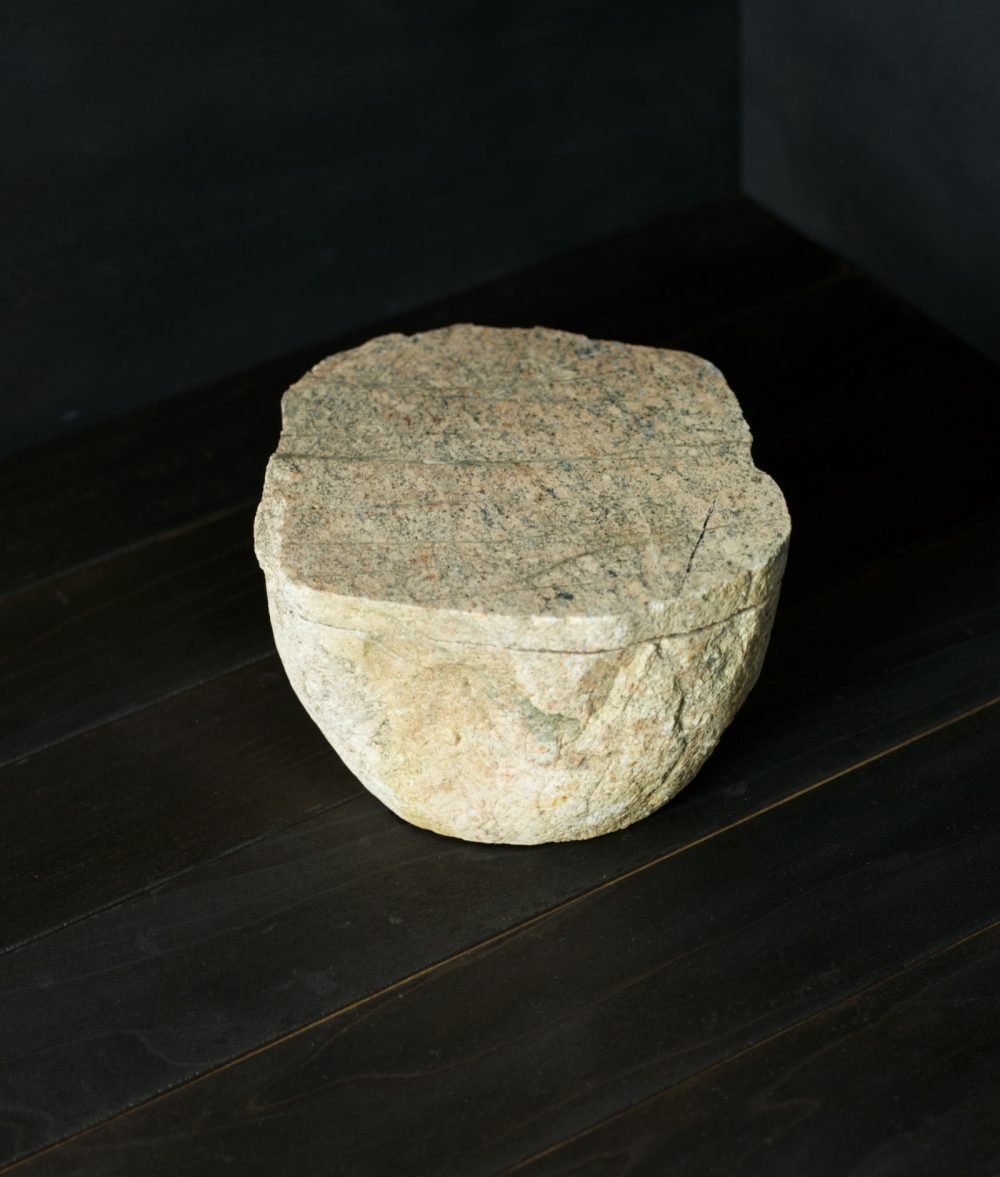 metamorphic stone bowl with yellow, white and green colors on top of a wooden background