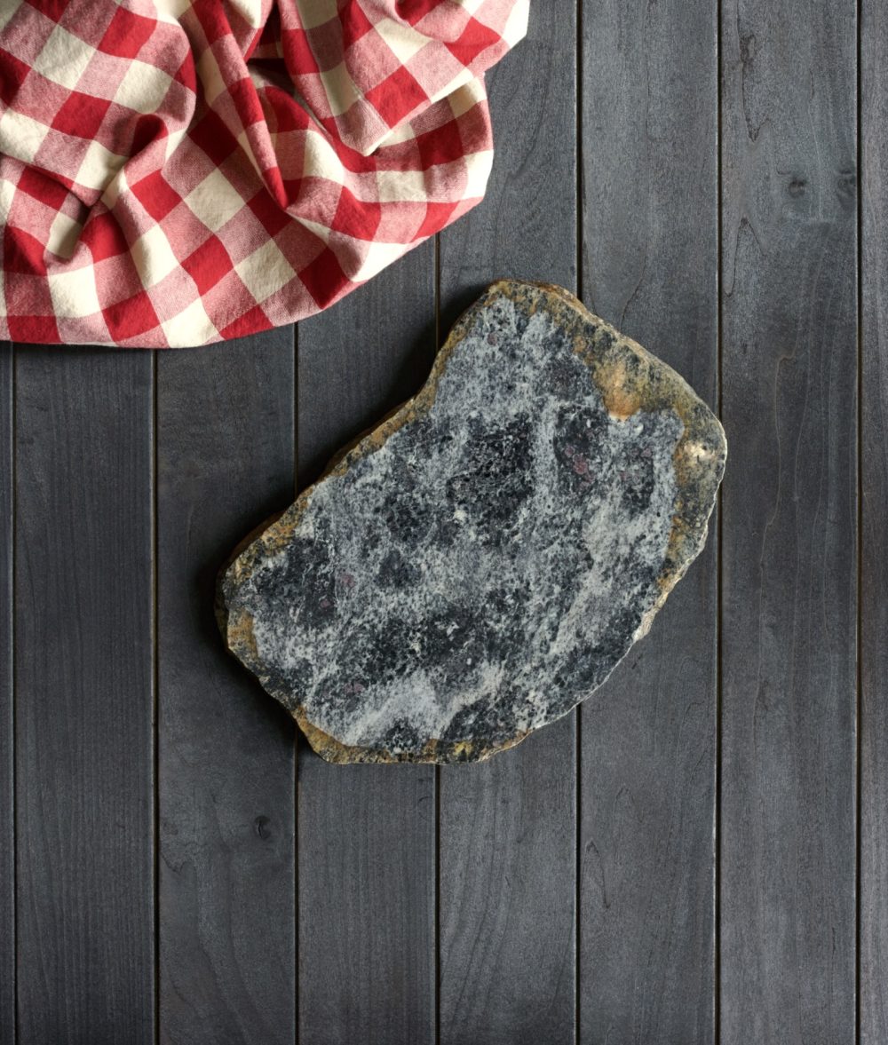 metamorphic stone charcuterie board with yellow, white and Black colors with red and white napkin on top of a wooden background
