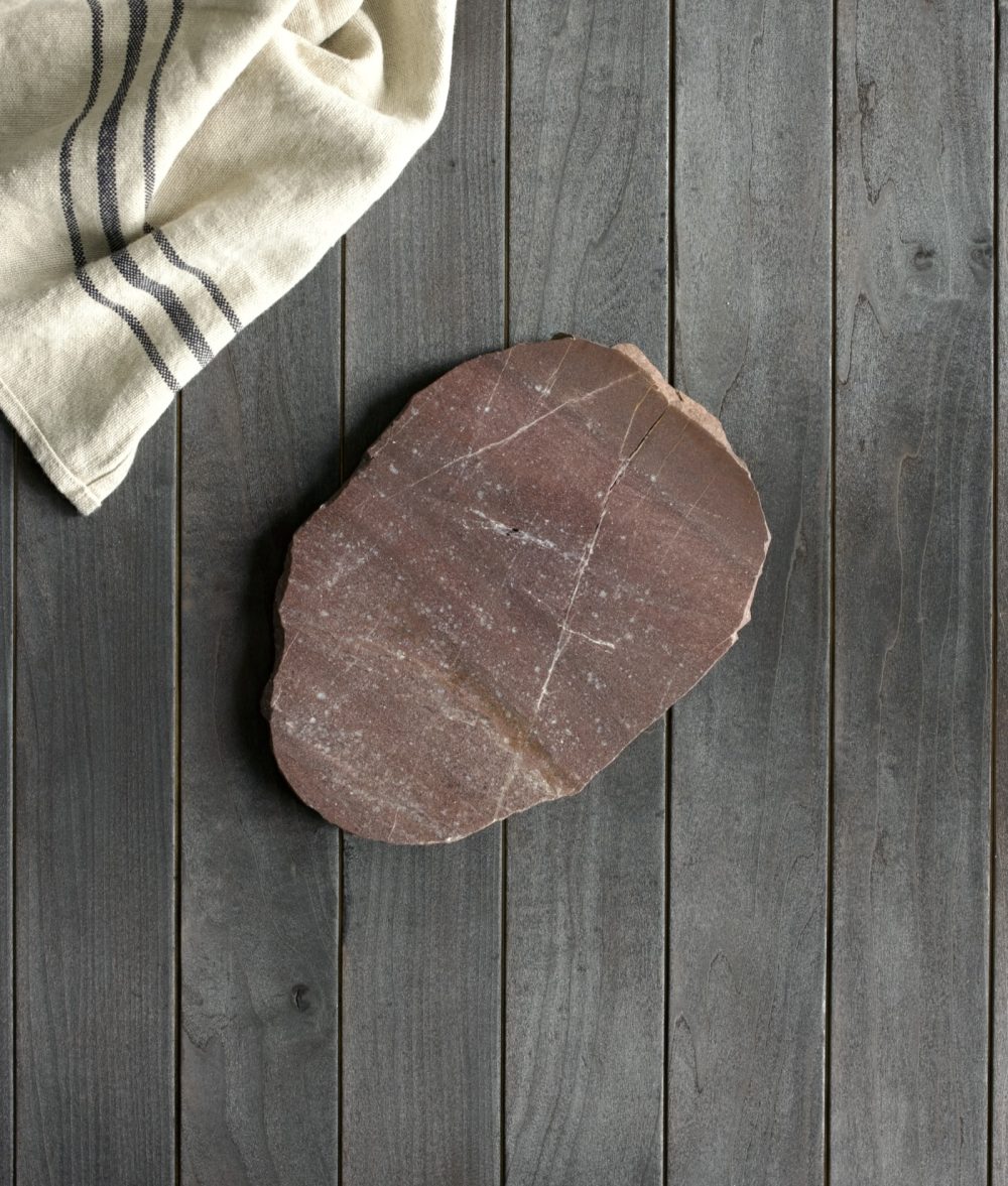 metamorphic stone charcuterie board with red, white and green colors with white napkin on top of a wooden background