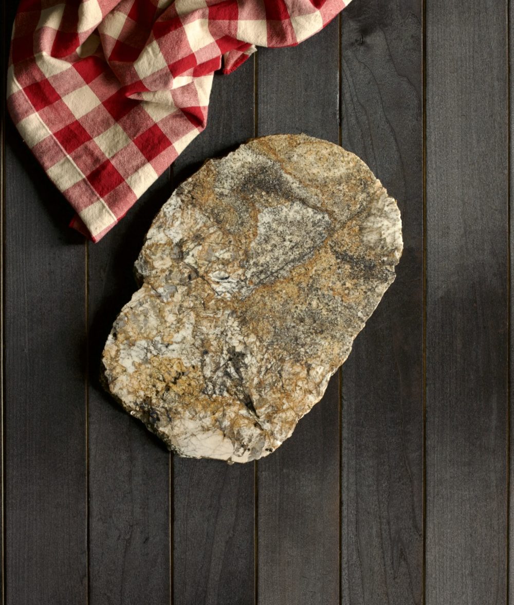 metamorphic stone charcuterie boards with gray and yellow colors with red and white napkin on top of a wooden background