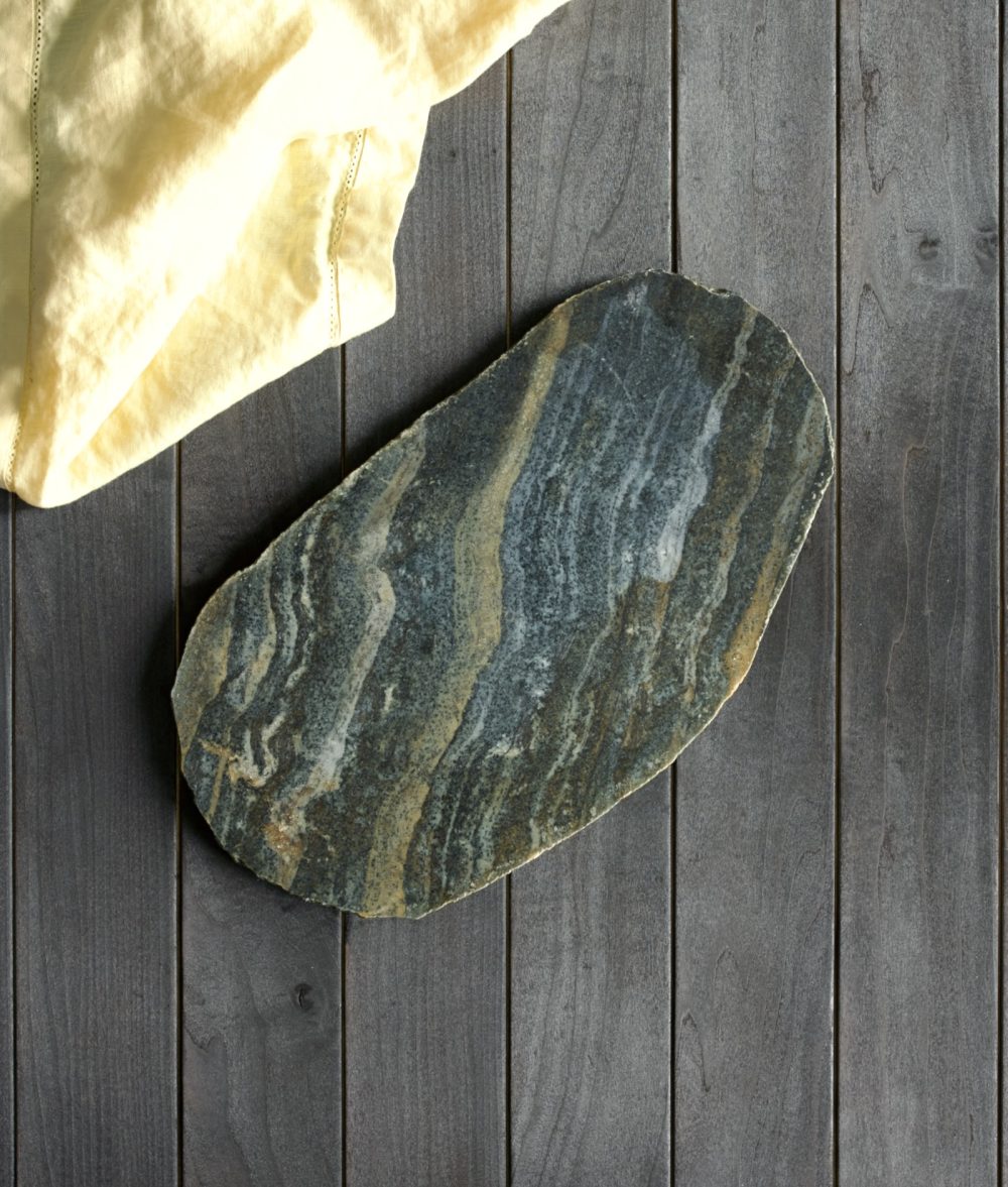 metamorphic stone charcuterie board with yellow, white and green colors with yellow napkin on top of a wooden background