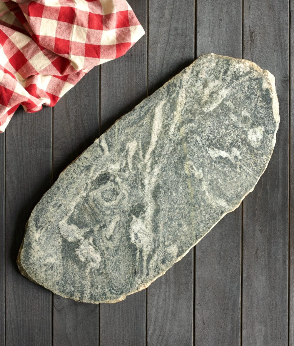 metamorphic stone charcuterie boards with gray, green and yellow colors with red and white napkin on top of a wooden background