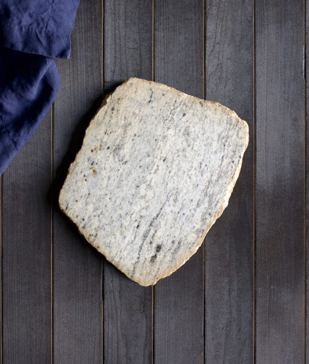 metamorphic stone charcuterie boards with gray, white and yellow colors with blue napkin on top of a wooden background