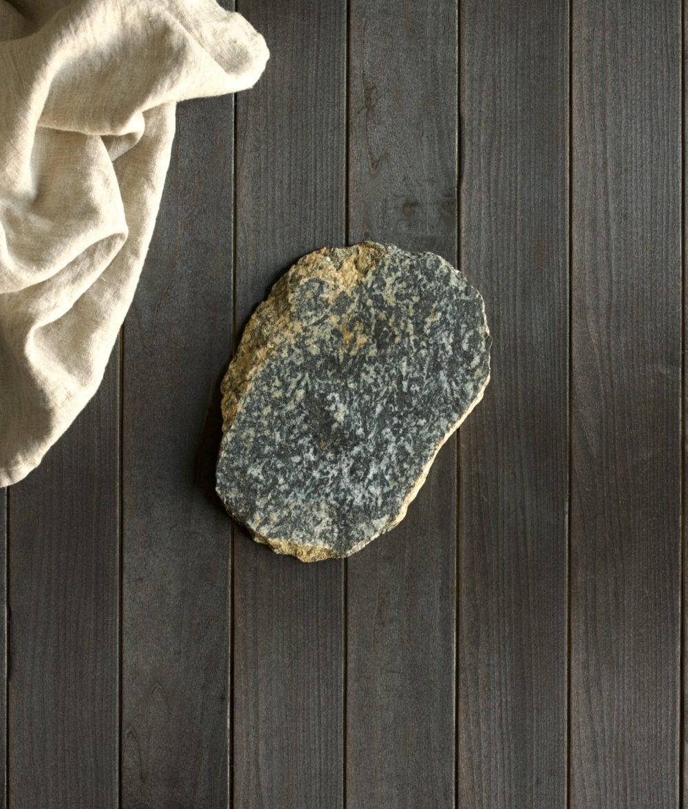 metamorphic stone trivet with gray and yellow colors on top of a wooden background with white napkin