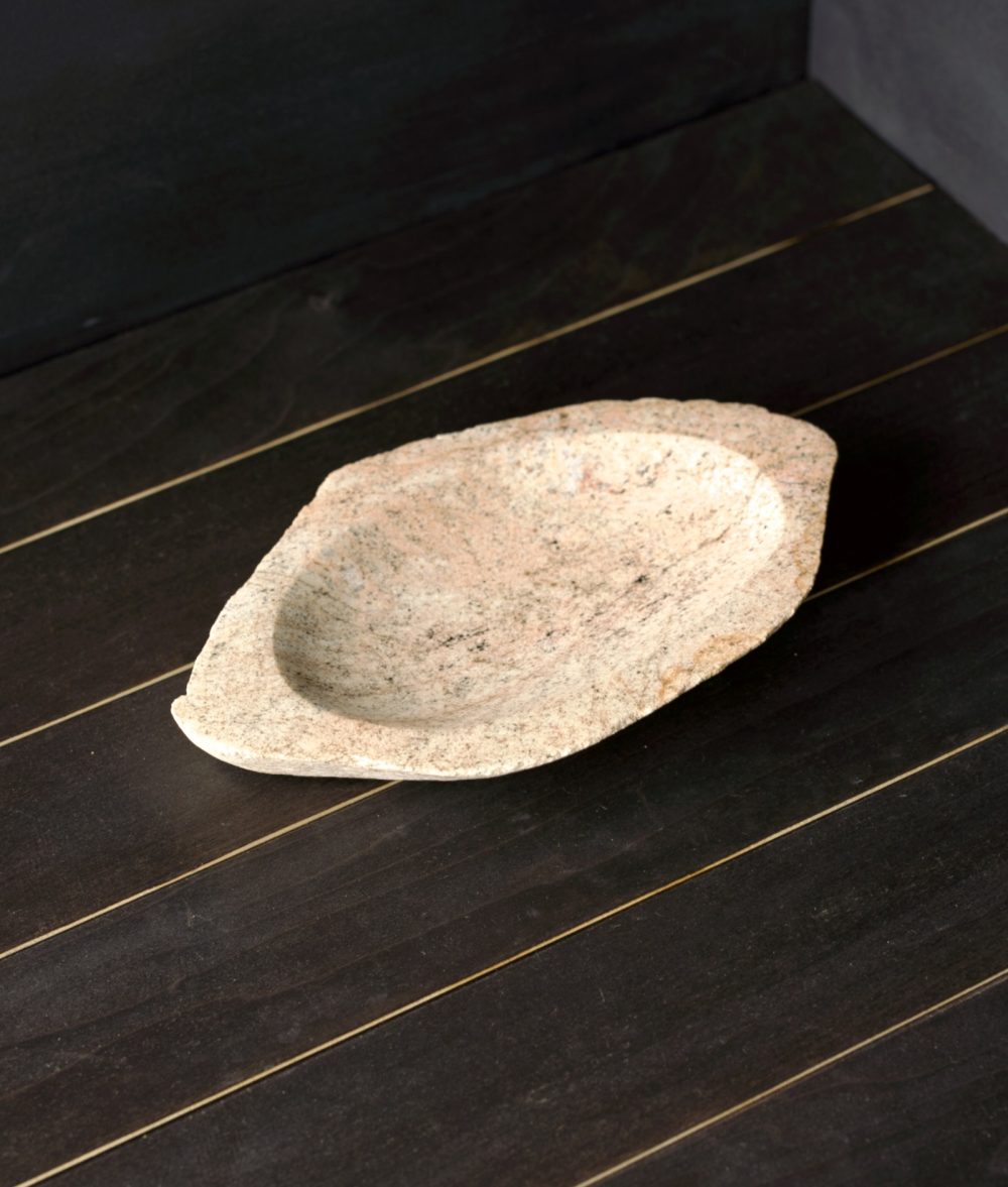 metamorphic stone bowl with gray, white and yellow colors on top of a wooden background