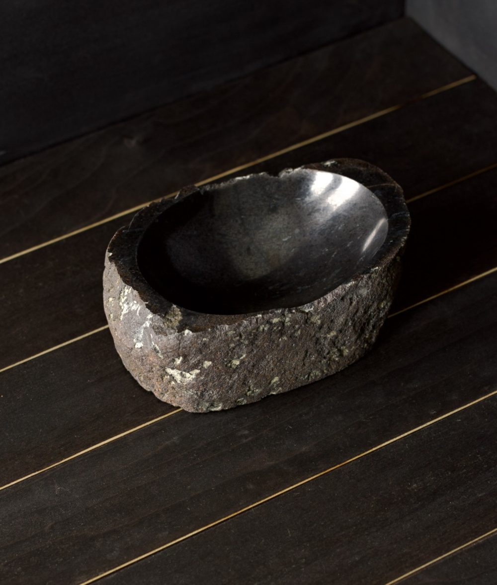 metamorphic stone bowl with gray, white and black colors on top of a wooden background