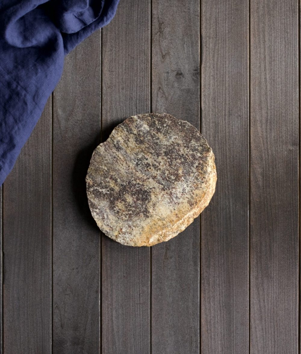 metamorphic stone charcuterie board with yellow, black and white colors with blue napkin on top of a wooden background