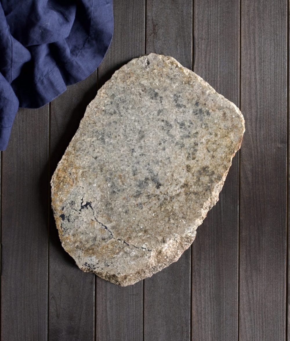 metamorphic stone charcuterie board with gray and white colors with blue napkin on top of a wooden background