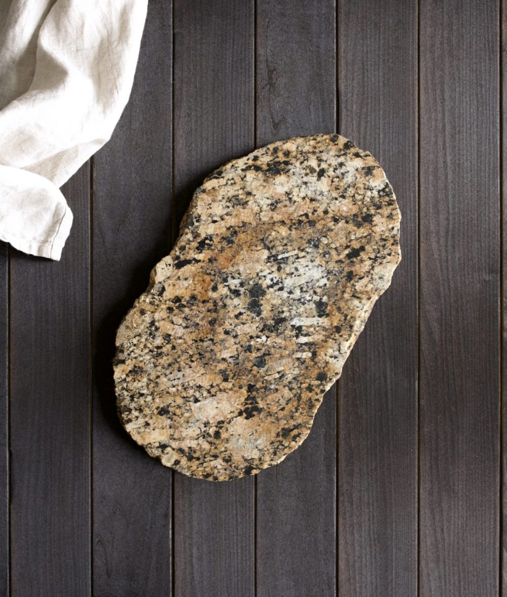 metamorphic stone charcuterie board with yellow, black and white colors with white napkin on top of a wooden background