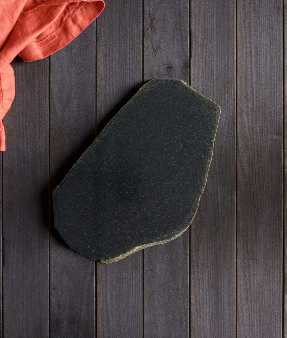 metamorphic stone charcuterie board with black and white colors with orange napkin on top of a wooden background