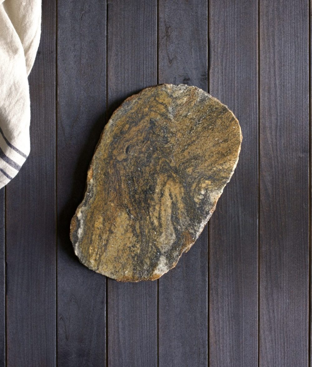 metamorphic stone charcuterie board with yellow, gray and black colors with white napkin on top of a wooden background