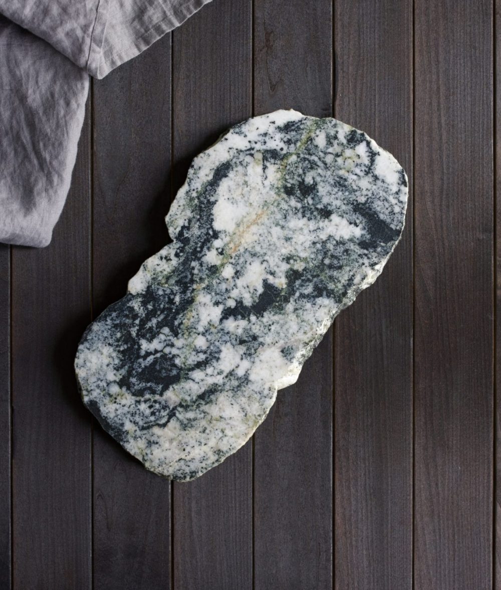 metamorphic stone charcuterie board with gray, blue and white colors with gray napkin on top of a wooden background