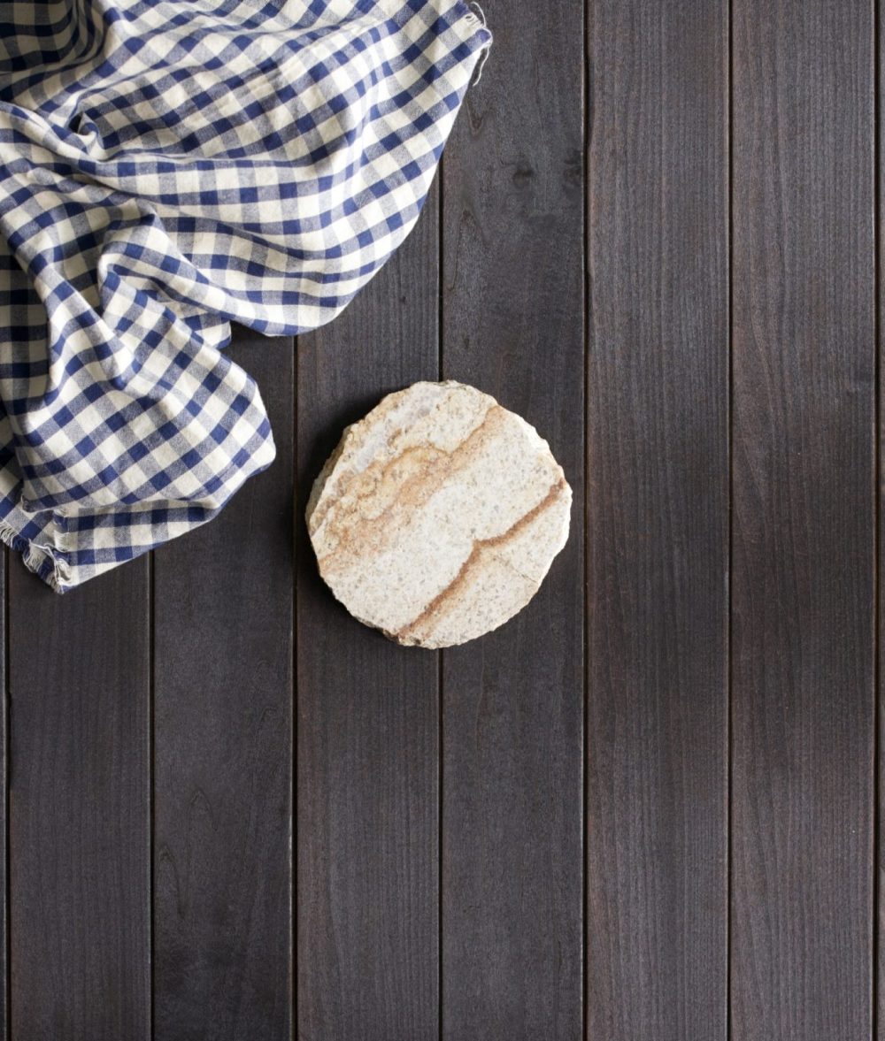 metamorphic stone coaster with white and yellow colors with white and black napkin on top of a wooden background
