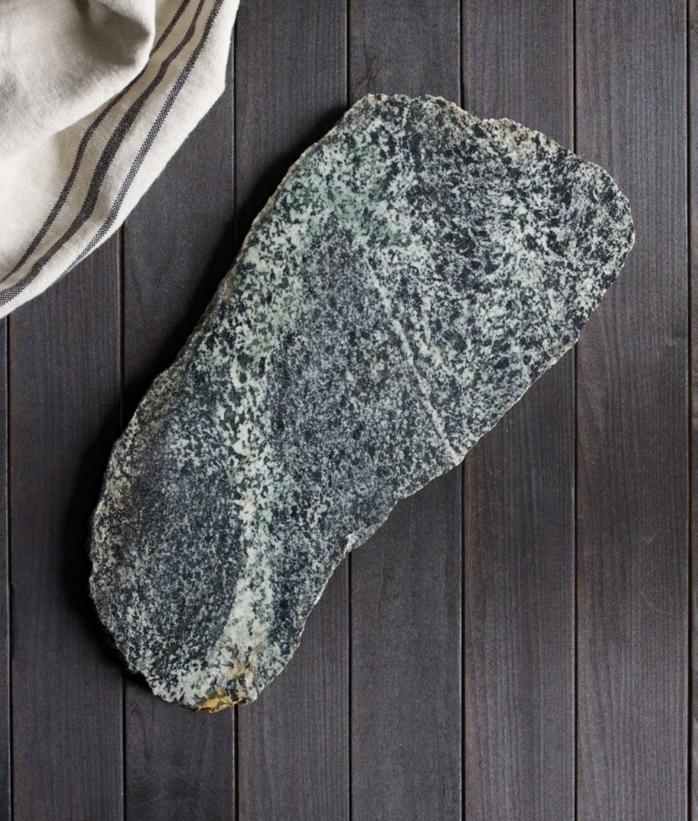 metamorphic stone charcuterie board with gray, green and white colors with white napkin on top of a wooden background